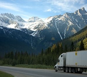 Semi truck driving in front of mountains