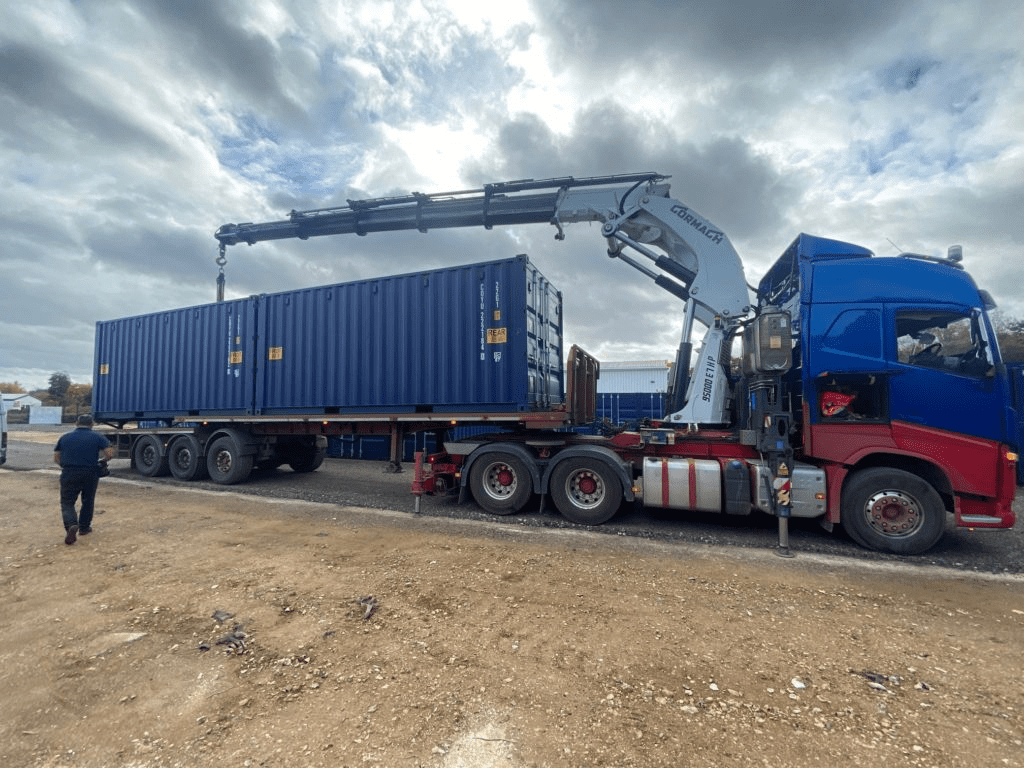 A shipping container being taken off of a tractor trailer.
